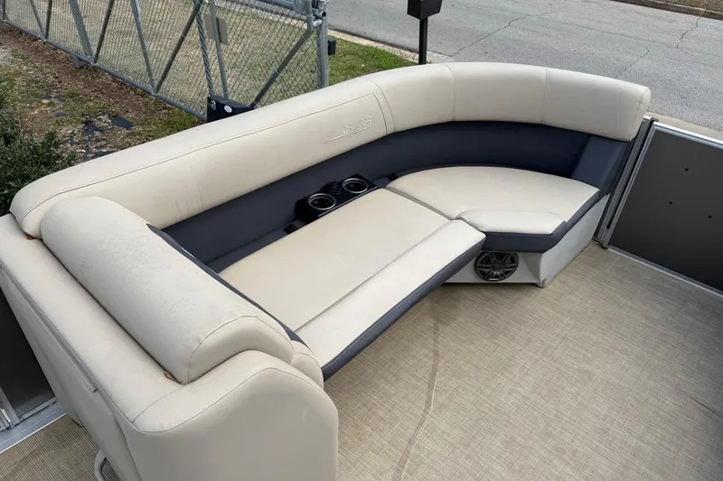 Slide: The Image of 2024 Harris Cruiser 230 boat interior with beige and gray seating, cup holders, and speaker. - 5
