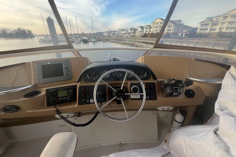Slide: The Image of 2004 Carver 366 Motor Yacht helm with steering wheel, navigation controls, and marina view. - 16