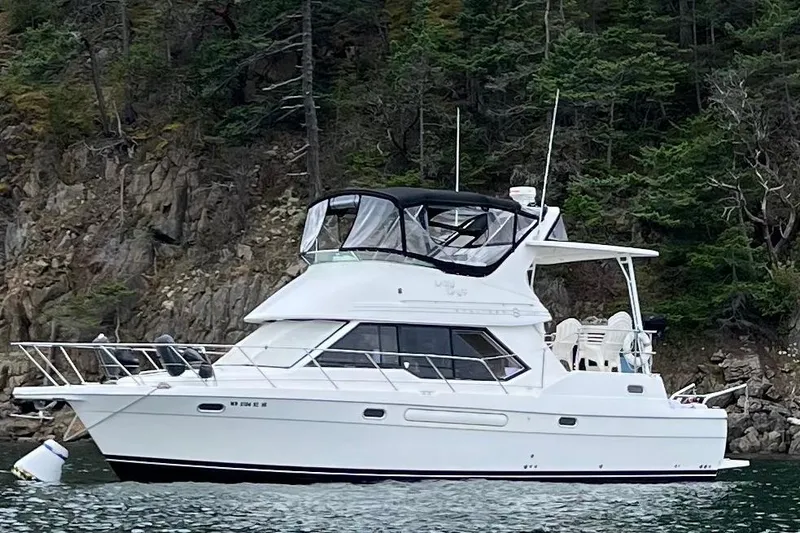 Slide: The Image of 1996 Bayliner 4087 Aft Cabin Motoryacht on water near rocky shoreline. - 2