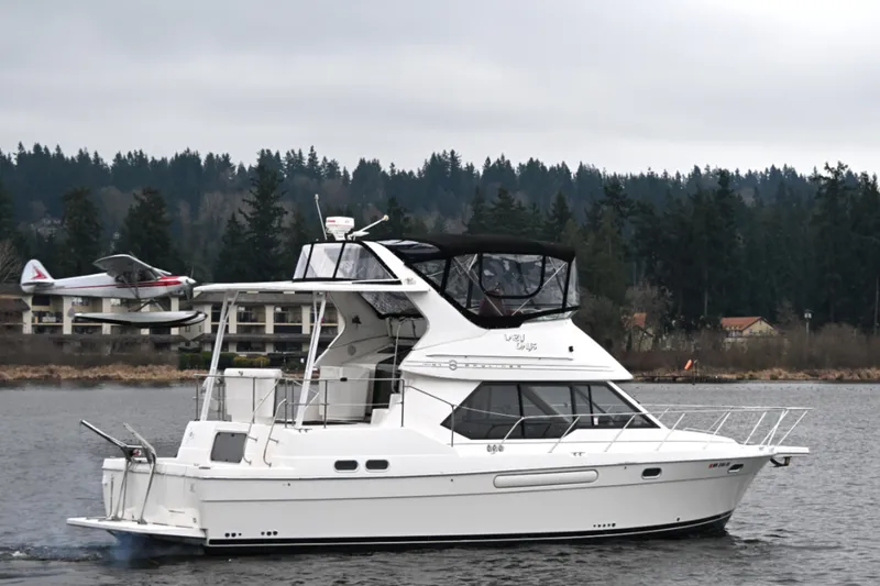 Slide: The Image of 1996 Bayliner 4087 Aft Cabin Motoryacht cruising on a lake with forested shoreline. - 4