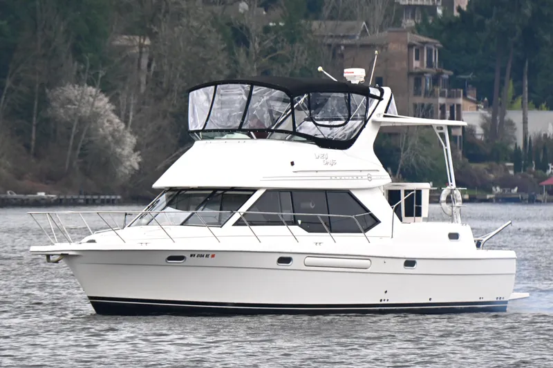 Slide: The Image of 1996 Bayliner 4087 Aft Cabin Motoryacht cruising on a calm lake with scenic background. - 6