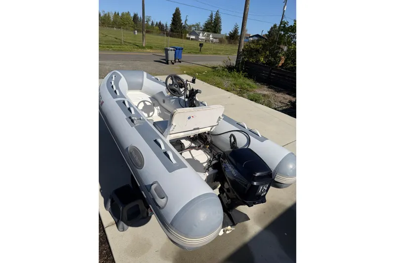 Slide: The Image of Inflatable boat with outboard motor on a sunny driveway, near Bayliner 4087 Aft Cabin Motoryacht. - 76