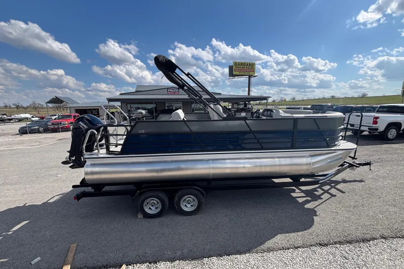 Slide: The Image of 2026 Berkshire 22UL LE B pontoon boat on trailer under a clear blue sky. - 3