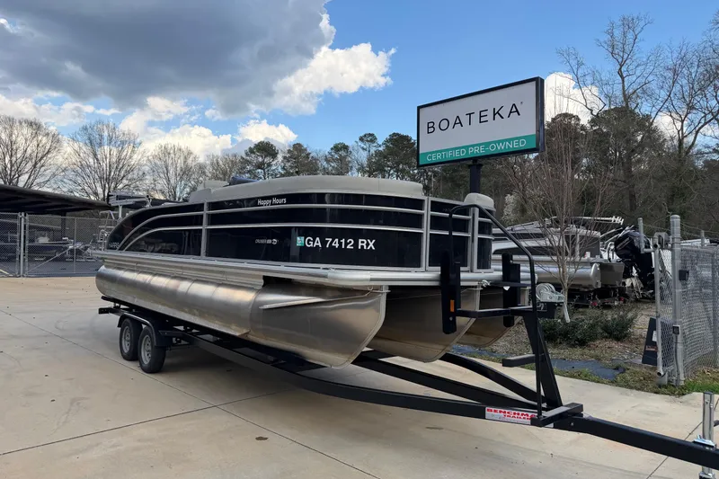 Slide: The Image of 2024 Harris Cruiser 230 pontoon boat on trailer at Boateka dealership. - 1