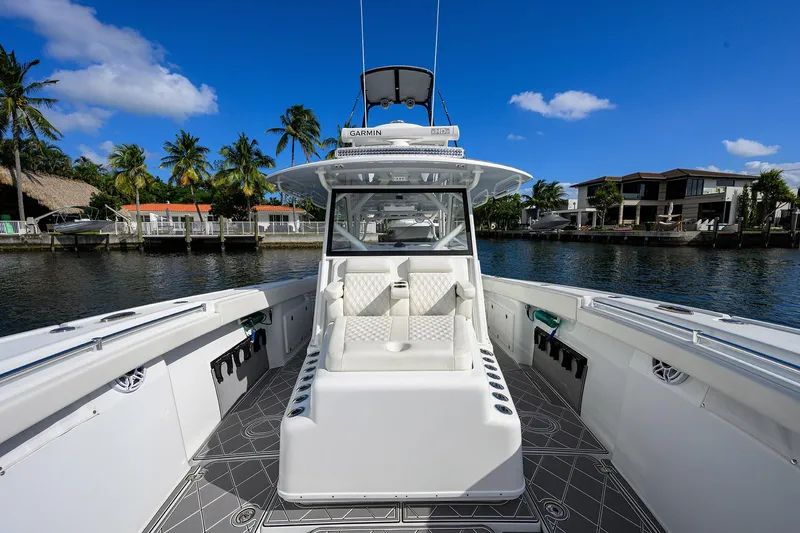 Slide: The Image of 2021 Yellowfin 42 boat with sleek design, docked near waterfront homes and palm trees. - 22