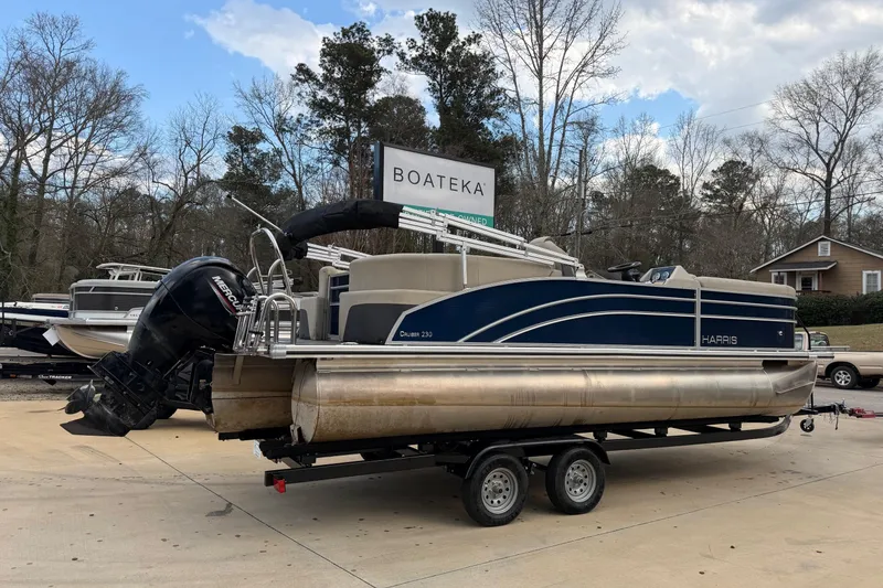Slide: The Image of 2023 Harris Cruiser 230 pontoon boat on trailer at Boateka dealership. - 2