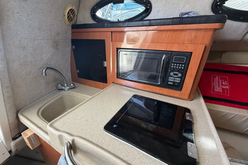 Slide: The Image of 2003 Wellcraft 270 Coastal O/B boat interior with kitchenette, sink, microwave, and stove. - 11