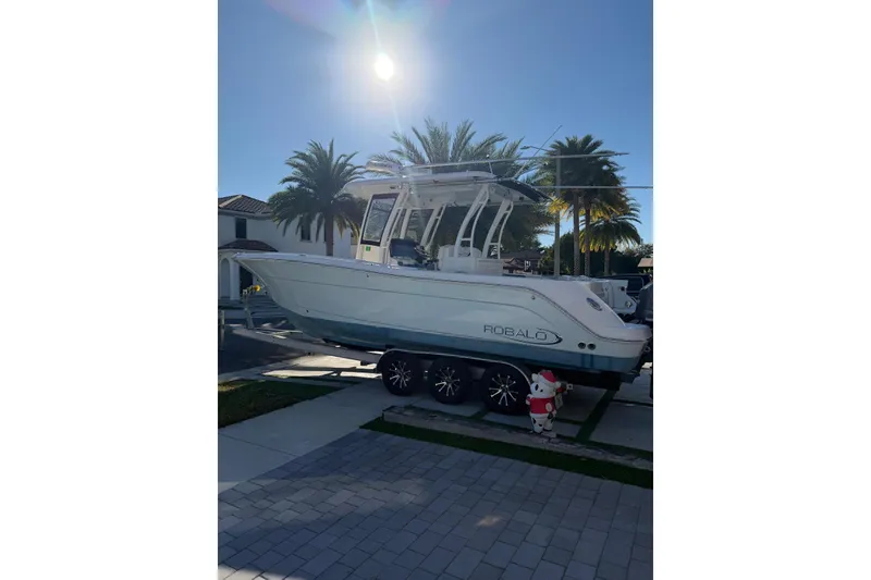 Slide: The Image of 2017 Robalo R302 Center Console boat on trailer, sunny day, palm trees in background. - 2