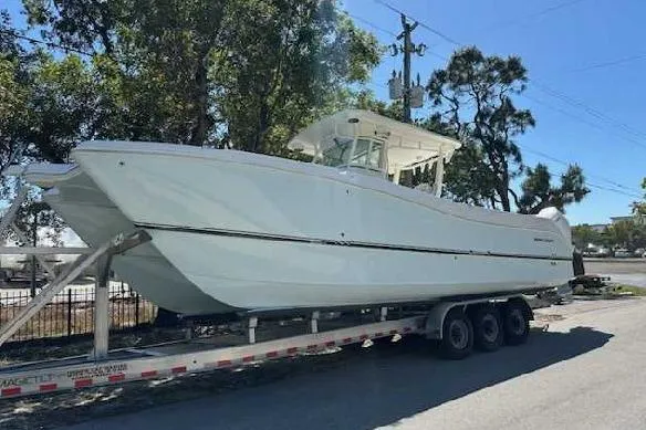 The Image of 2025 World Cat 325 CC boat on trailer, parked outdoors under trees. - 0