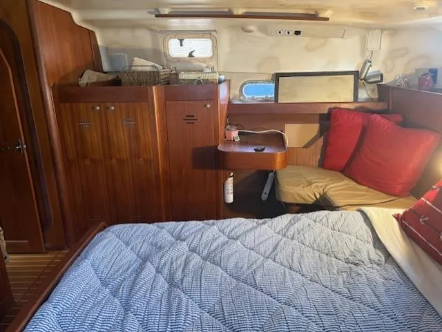 Slide: The Image of 1999 Hunter Passage 450 yacht interior with bed, wooden cabinets, and red cushions. - 10