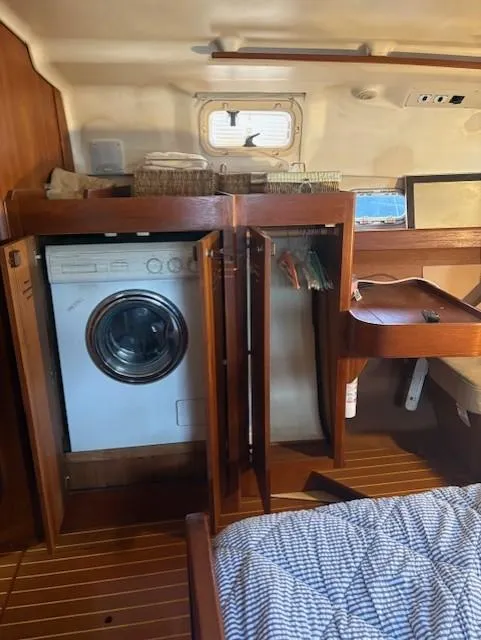 Slide: The Image of 1999 Hunter Passage 450 yacht interior with washer, wooden cabinetry, and cozy bedding. - 12