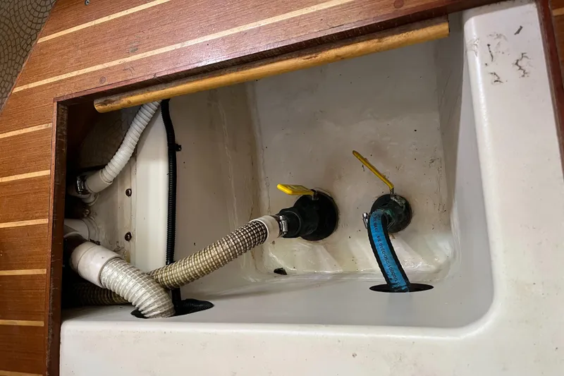 Slide: The Image of Interior plumbing of 1999 Hunter Passage 450 sailboat with visible hoses and valves. - 14