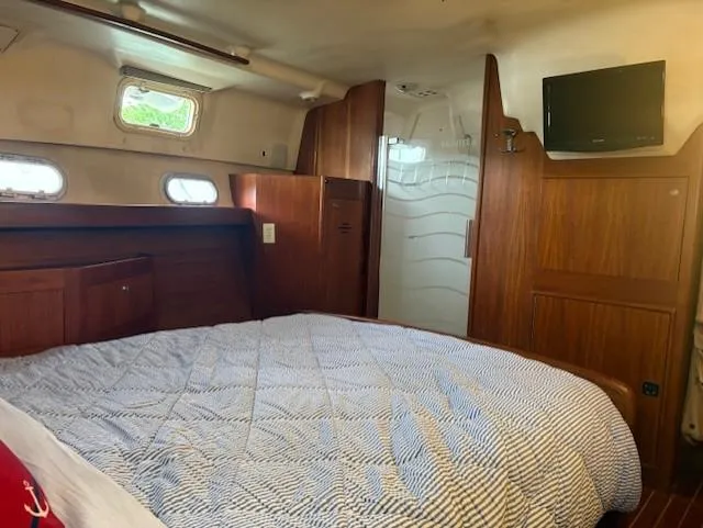Slide: The Image of Cozy cabin interior of 1999 Hunter Passage 450 yacht with bed, wood paneling, and small windows. - 9