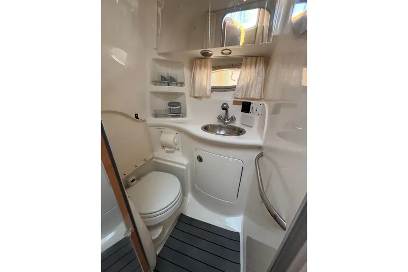 Slide: The Image of 2006 Chaparral Signature 310 boat bathroom with toilet, sink, and storage shelves. - 8