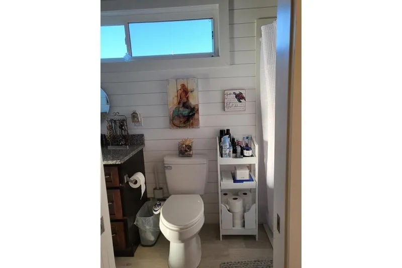 Slide: The Image of Modern bathroom in 2021 Harbor Cottage, featuring white shiplap walls and compact storage. - 10