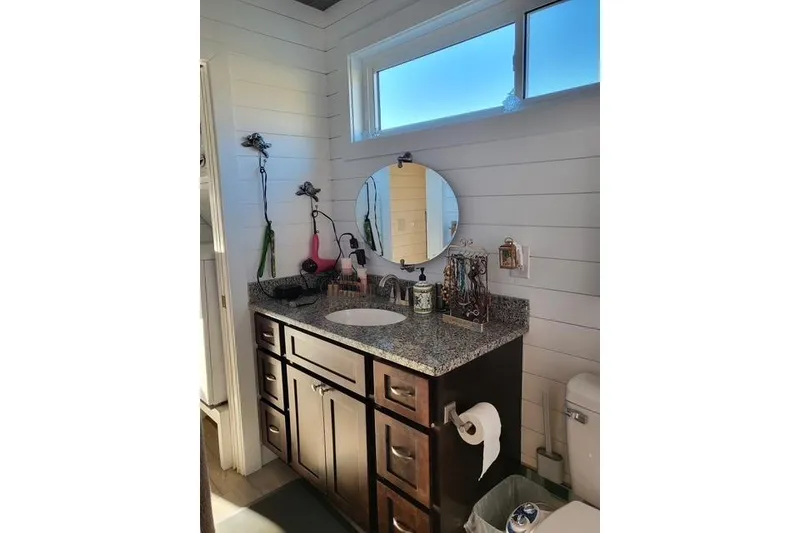 Slide: The Image of Modern bathroom vanity in 2021 Harbor Cottage, featuring granite countertop and round mirror. - 22