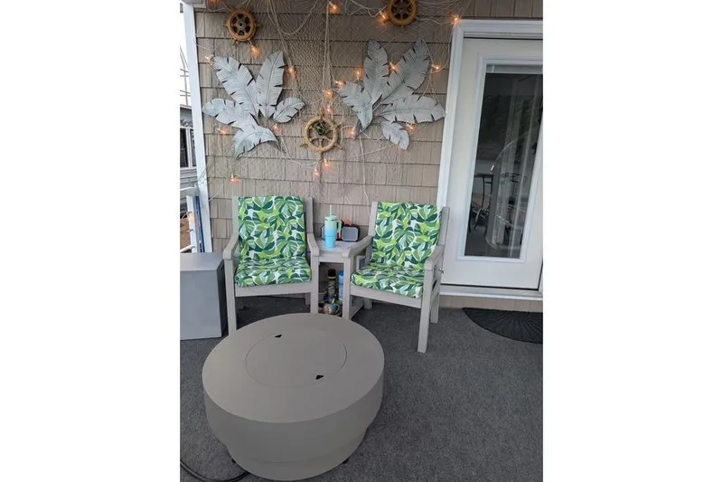 Slide: The Image of Cozy patio with leaf-patterned chairs, decorative wall art, and a round table. Harbor Cottage 2021. - 26