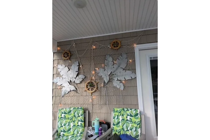 Slide: The Image of Decorative porch with leaf wall art, netting, and string lights; Harbor Cottage 2021 model. - 27