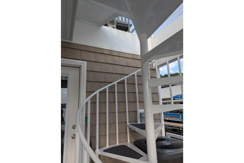 Slide: The Image of White spiral staircase in a 2021 Harbor Cottage model, leading to an upper deck. - 29