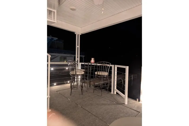 Slide: The Image of Cozy Harbor Cottage 2021 model balcony with chairs, table, and ambient lighting at night. - 33