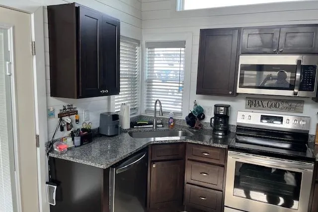 Slide: The Image of Modern kitchen in a 2021 Harbor Cottage, featuring dark cabinets and stainless steel appliances. - 5