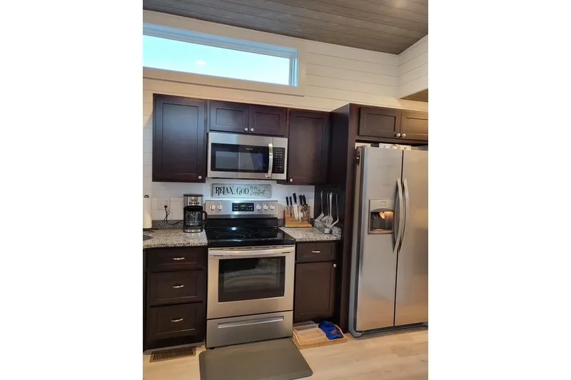 Slide: The Image of Modern kitchen in 2021 Harbor Cottage with stainless steel appliances and dark wood cabinets. - 6