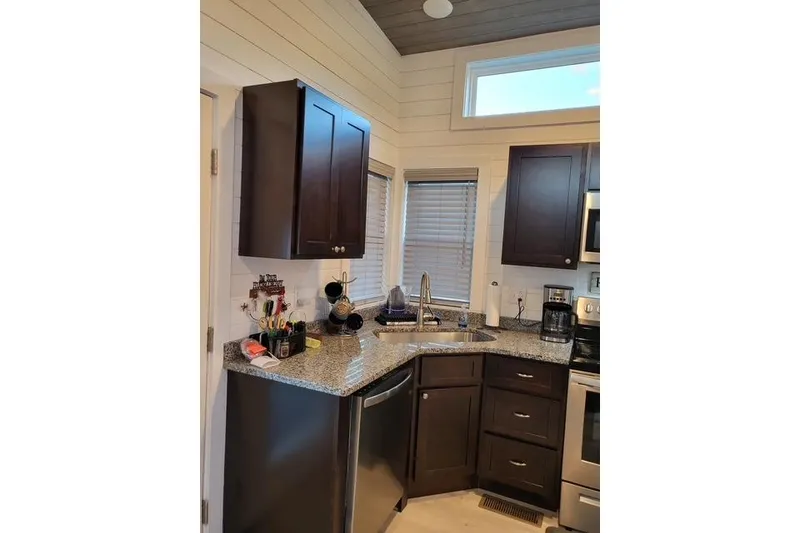 Slide: The Image of Modern kitchen in 2021 Harbor Cottage, featuring dark cabinets and granite countertops. - 7
