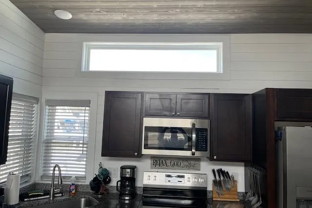 Slide: The Image of Modern kitchen interior in 2021 Harbor Cottage, featuring dark cabinets and stainless steel appliances. - 9