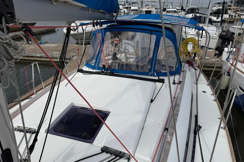 Slide: The Image of 2018 Jeanneau Sun Odyssey 389 sailboat docked at marina, featuring blue canopy and sleek deck design. - 18