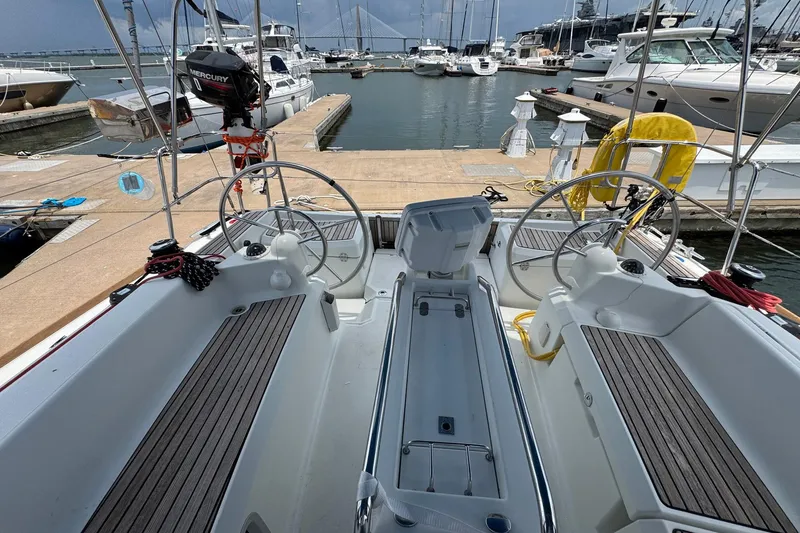 Slide: The Image of 2018 Jeanneau Sun Odyssey 389 sailboat cockpit at marina, featuring dual steering wheels. - 22