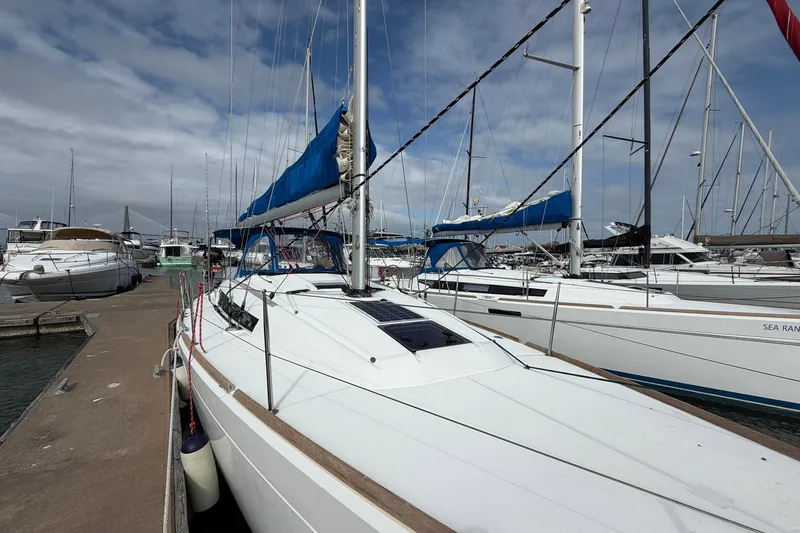 Slide: The Image of 2018 Jeanneau Sun Odyssey 389 sailboat docked in a marina under a cloudy sky. - 5