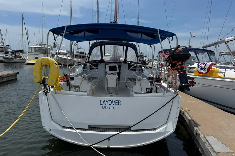 Slide: The Image of 2018 Jeanneau Sun Odyssey 389 sailboat docked at marina, featuring blue canopy and outboard motor. - 7