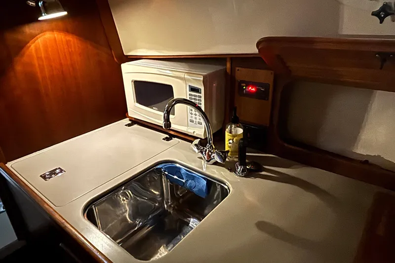 Slide: The Image of 2004 Hinckley 36 Picnic Boat EP galley with sink, microwave, and wooden cabinetry. - 4