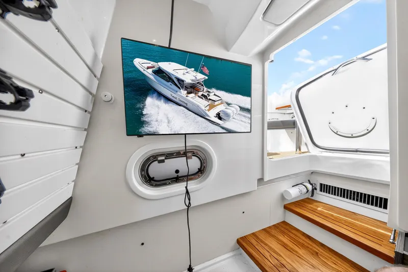 Slide: The Image of 2022 Tiara Yachts 38 LX interior with TV displaying yacht image, wooden steps, and porthole. - 42