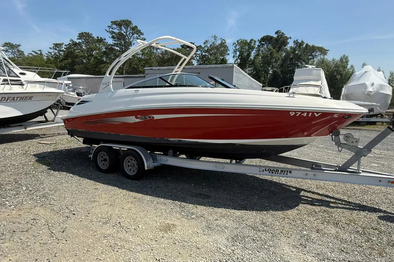The Image of 2014 Sea Ray 240 Sundeck Outboard boat on trailer, red and white design. - 1