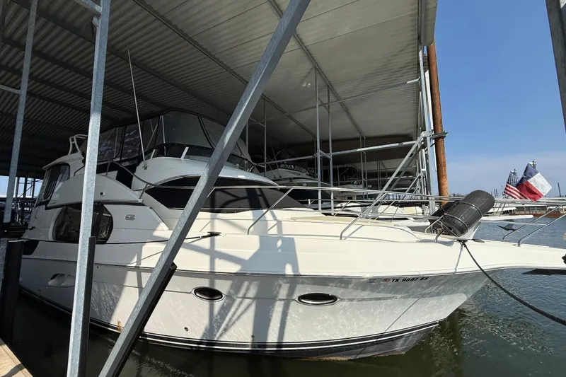 Slide: The Image of 2005 Silverton 43 Motor Yacht docked under a covered marina with flags in the background. - 10