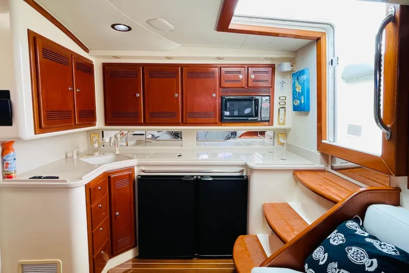 Slide: The Image of Luxurious 1998 Cabo 45 Express yacht interior with wooden cabinets and modern kitchen amenities. - 10