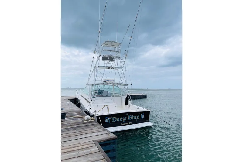 Slide: The Image of 1998 Cabo 45 Express boat docked under cloudy skies, named "Deep Blue." - 4