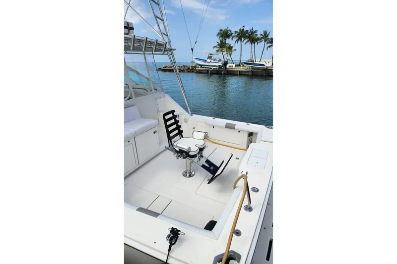 Slide: The Image of 1998 Cabo 45 Express boat deck with fishing chair, docked near palm trees. - 6