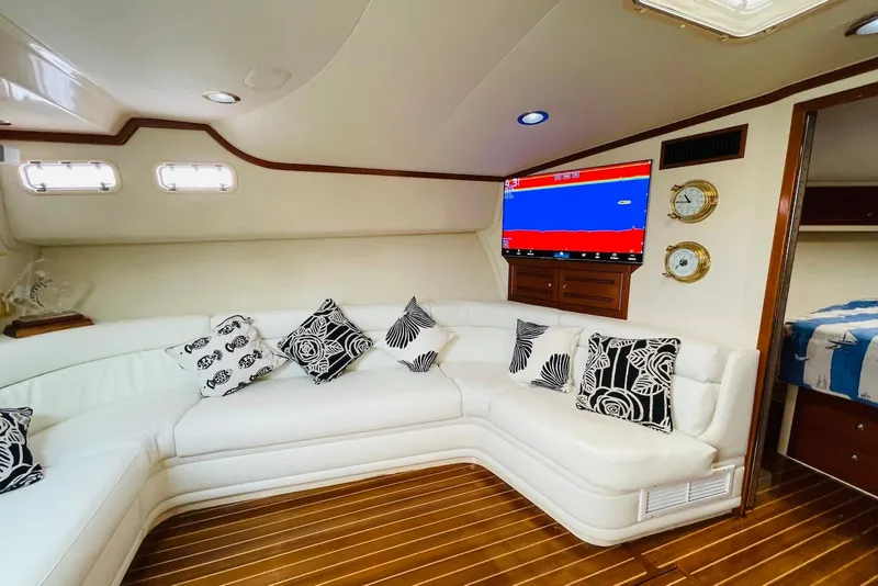 Slide: The Image of Luxurious 1998 Cabo 45 Express yacht interior with white seating, patterned cushions, and mounted TV. - 8