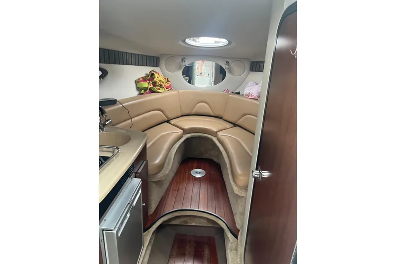 Slide: The Image of 2016 Crownline 264 CR cabin interior with tan seating and kitchenette. - 11