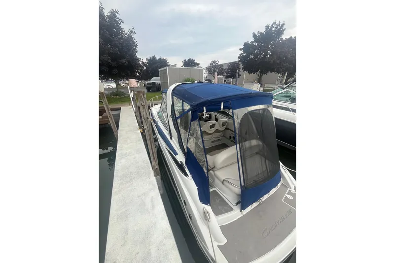 Slide: The Image of 2016 Crownline 264 CR boat docked with blue canopy and white interior. - 5