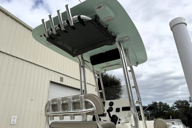 Slide: The Image of 2024 Key West 203 FS boat with T-top and rod holders, parked near a building. - 14