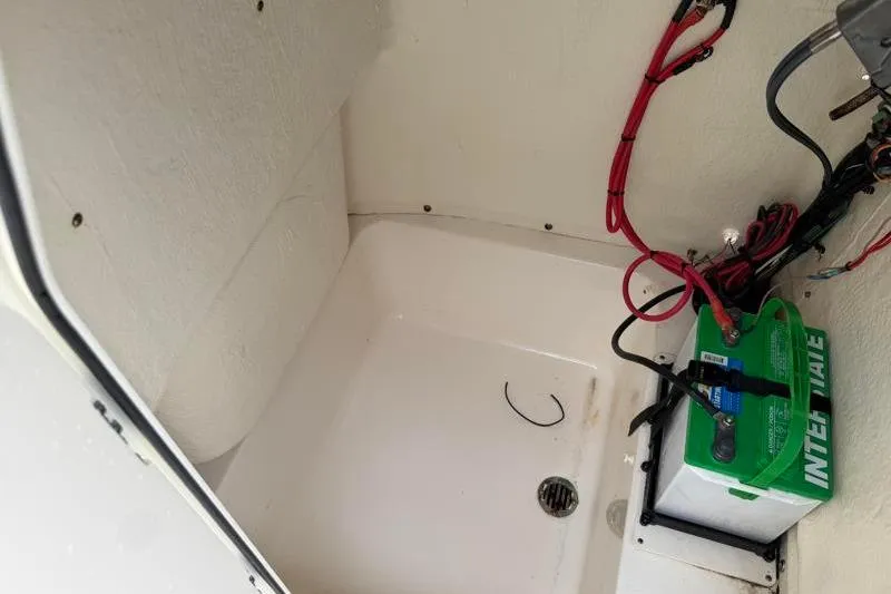 Slide: The Image of 2024 Key West 203 FS boat battery compartment with wiring and drainage. - 25