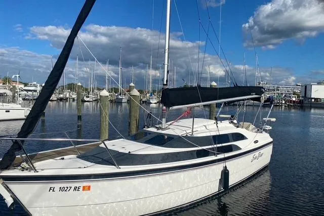 The Image of 2011 MacGregor 26M sailboat docked in a marina under a blue sky. - 1