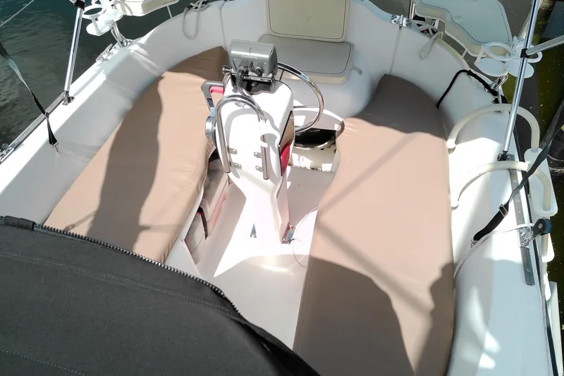 Slide: The Image of 2011 MacGregor 26M sailboat cockpit with beige seating and steering wheel. - 10