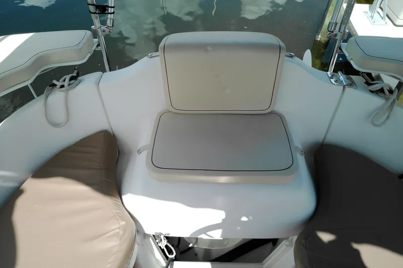 Slide: The Image of 2011 MacGregor 26M boat seating area with cushioned seats and ropes. - 11