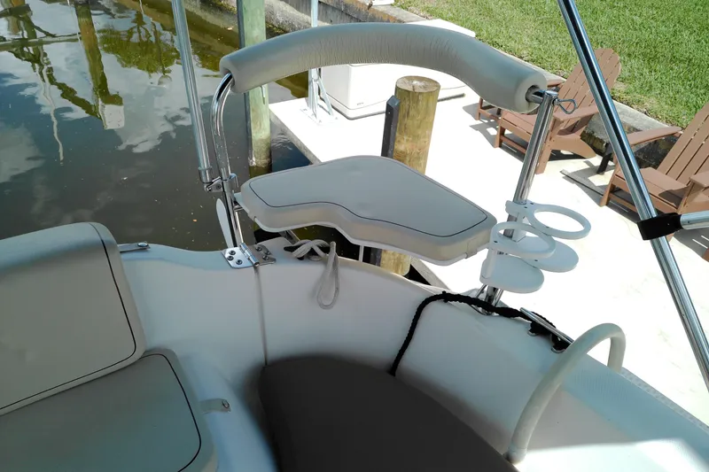 Slide: The Image of MacGregor 26M 2011 boat cockpit with cushioned seating and cup holders. - 13