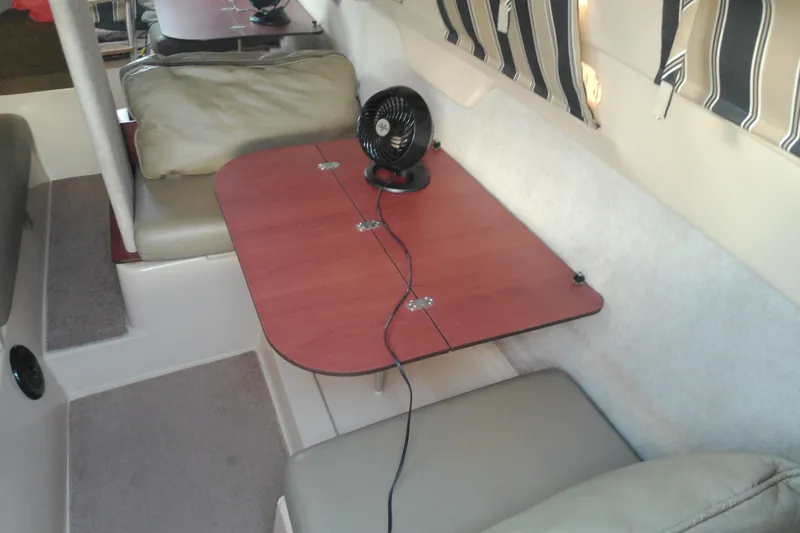 Slide: The Image of Interior of a 2011 MacGregor 26M sailboat with a foldable table and fan. - 18