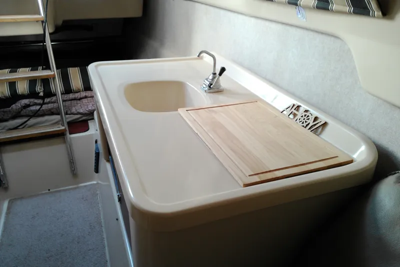 Slide: The Image of Compact kitchen area in a 2011 MacGregor 26M sailboat with sink and cutting board. - 27